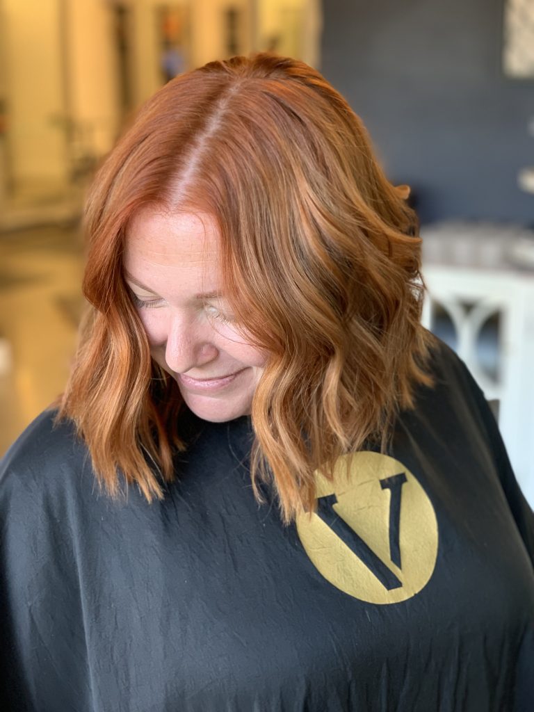 woman in hair salon with bold red hair color